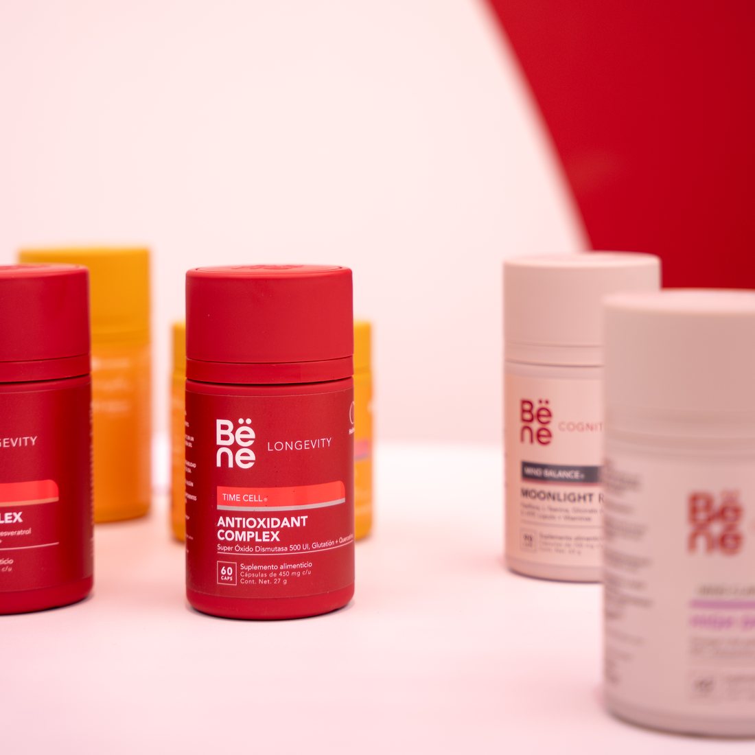 Frascos de Bëne Antioxidant Complex y Moonlight Ritual frente a un arco rojo