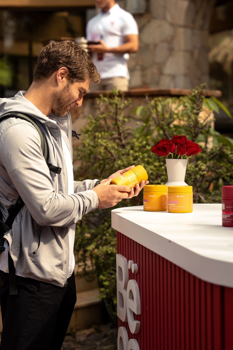 Invitado revisando un frasco de Bëne Essentials en el stand de la marca